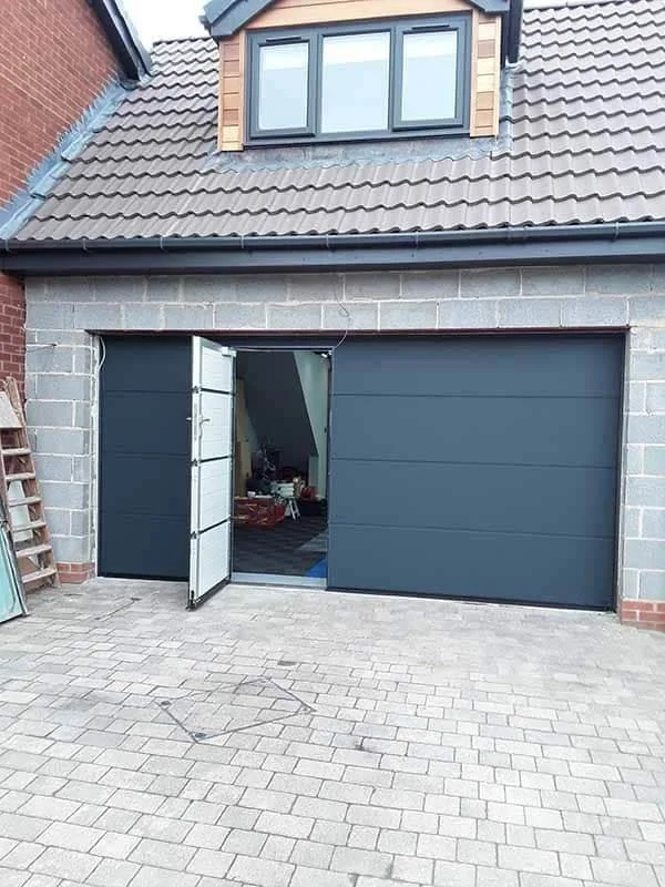 Front view of a garage door with a built-in door and handle, closed